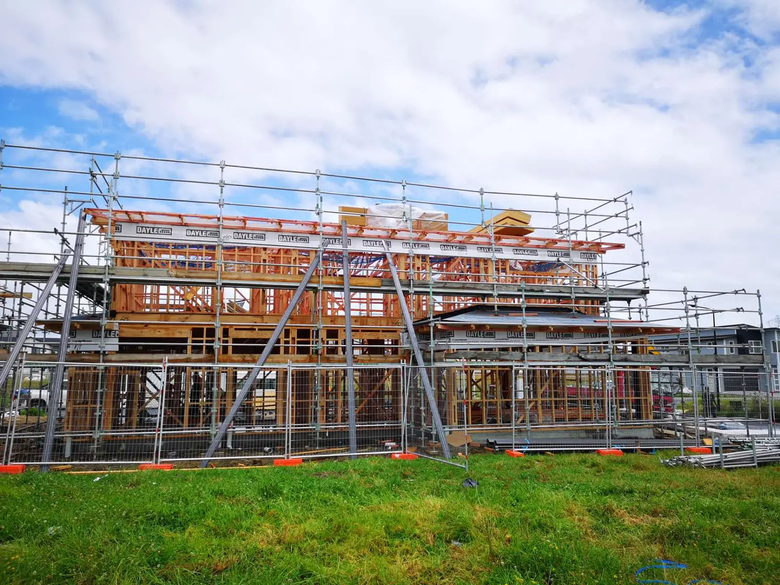 Two-storey timber frame wrapped in scaffolding and roof underlay