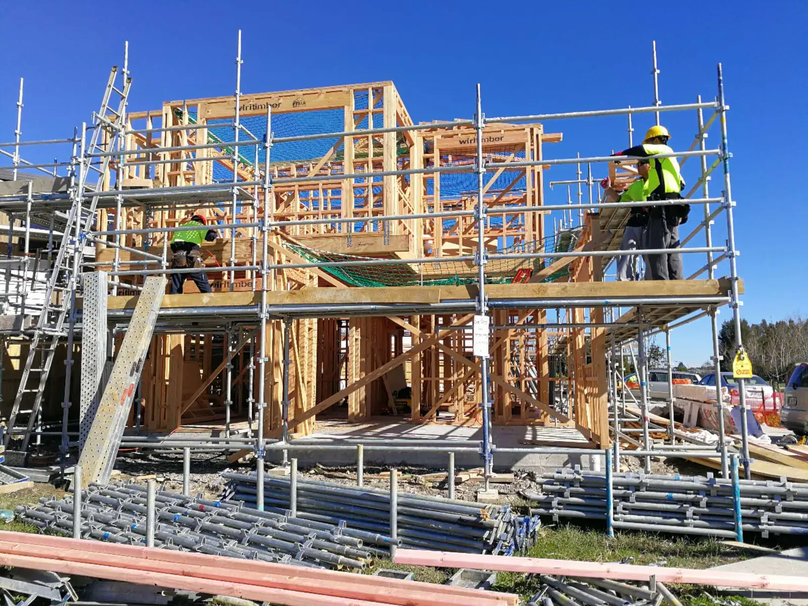 Builders working from scaffolding on an upper-floor timber frame