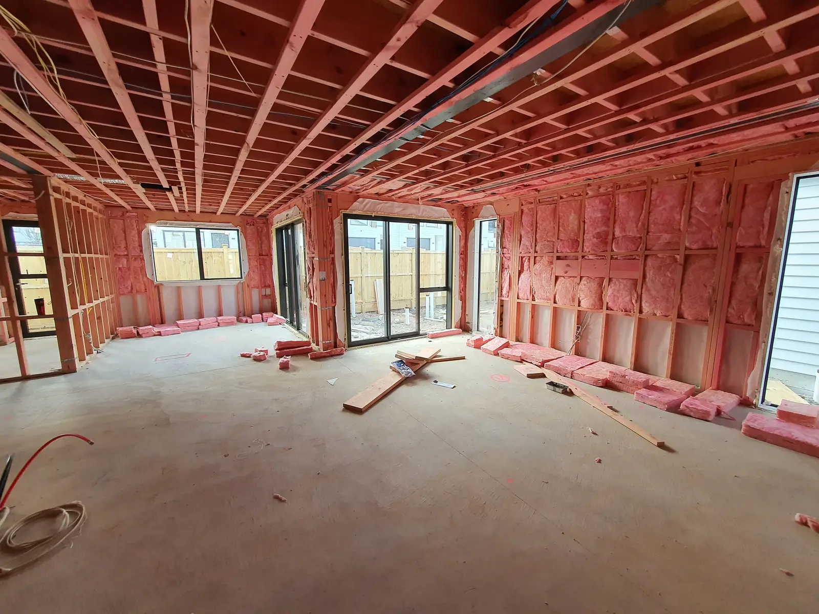 Ground-floor interior with insulation fitted between wall studs and exposed floor joists above