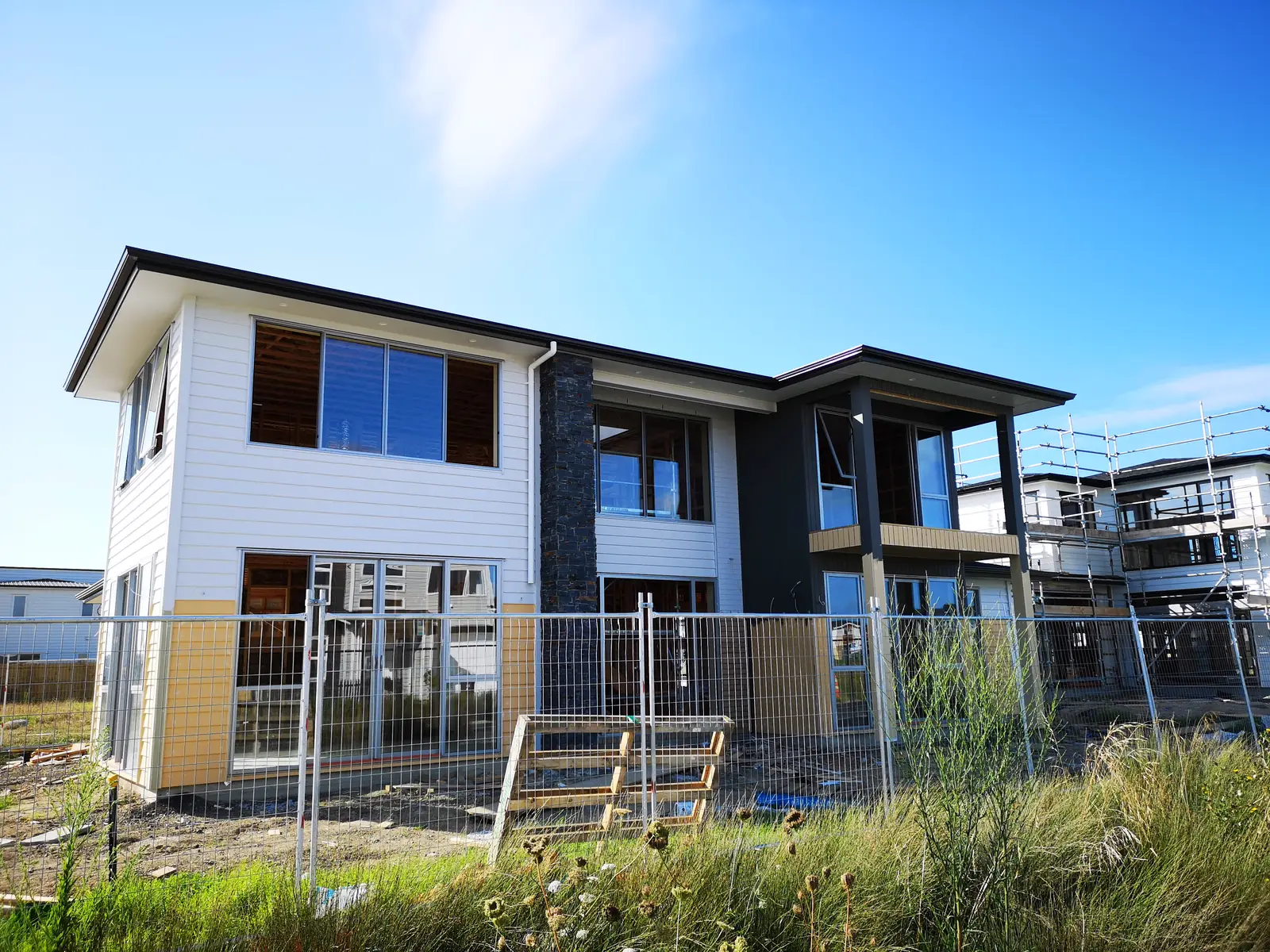 Two-storey home nearing completion with weatherboard cladding and a stacked stone feature column