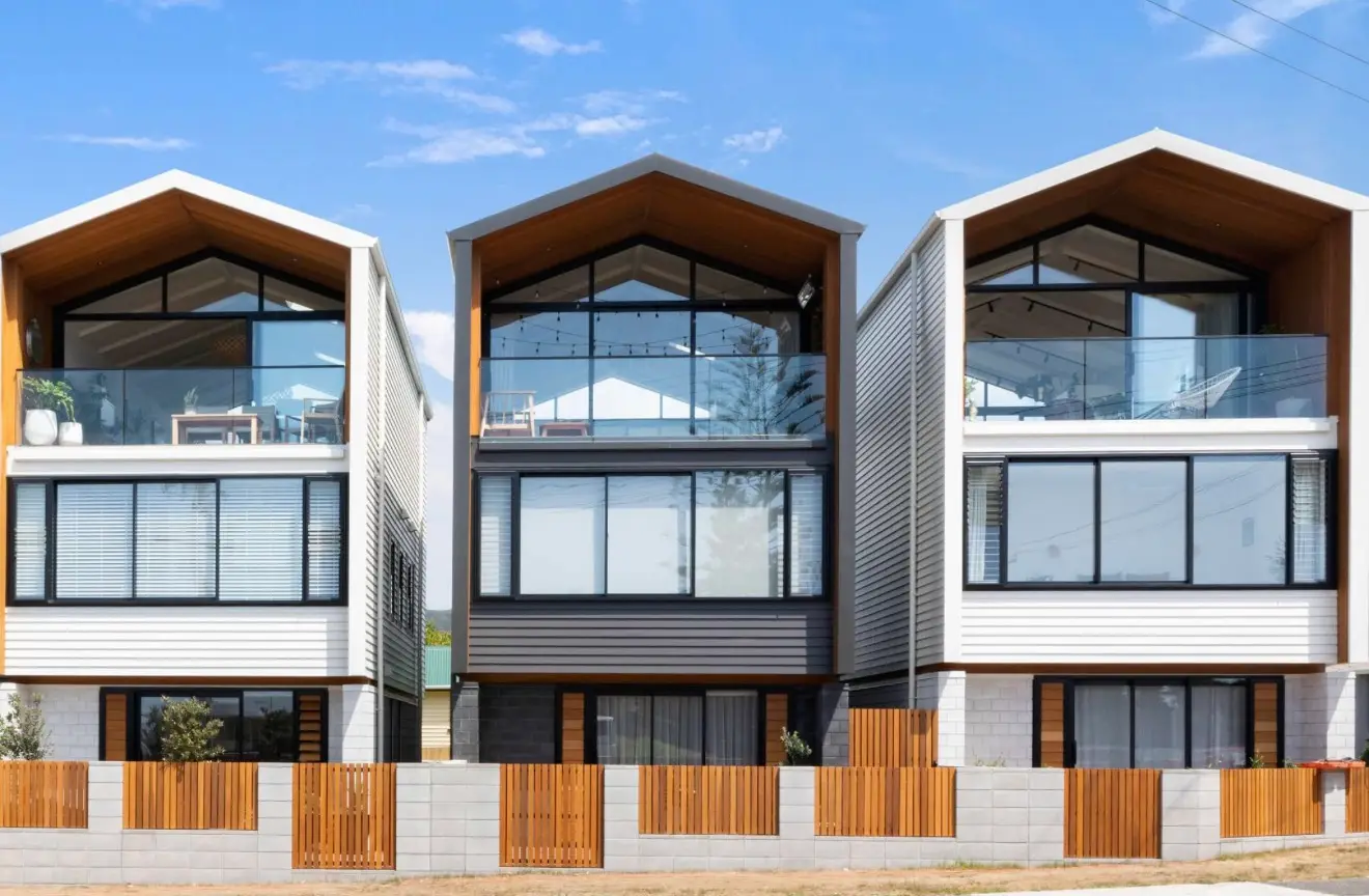 Row of three gabled townhouses with cedar-lined soffits and glass balconies