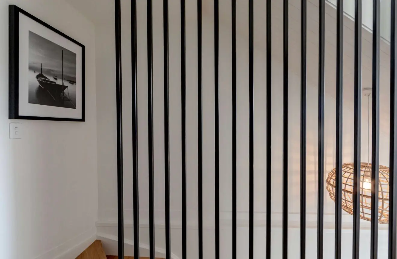 Black vertical batten stair screen beside a white stairwell
