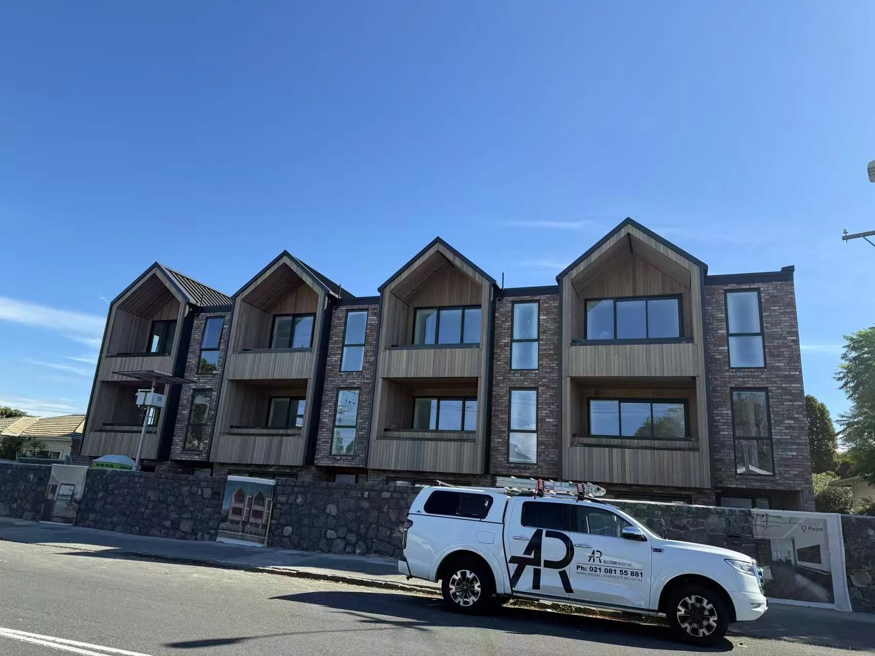 Completed multi-unit townhouse development with gabled cedar-lined entries and brick cladding